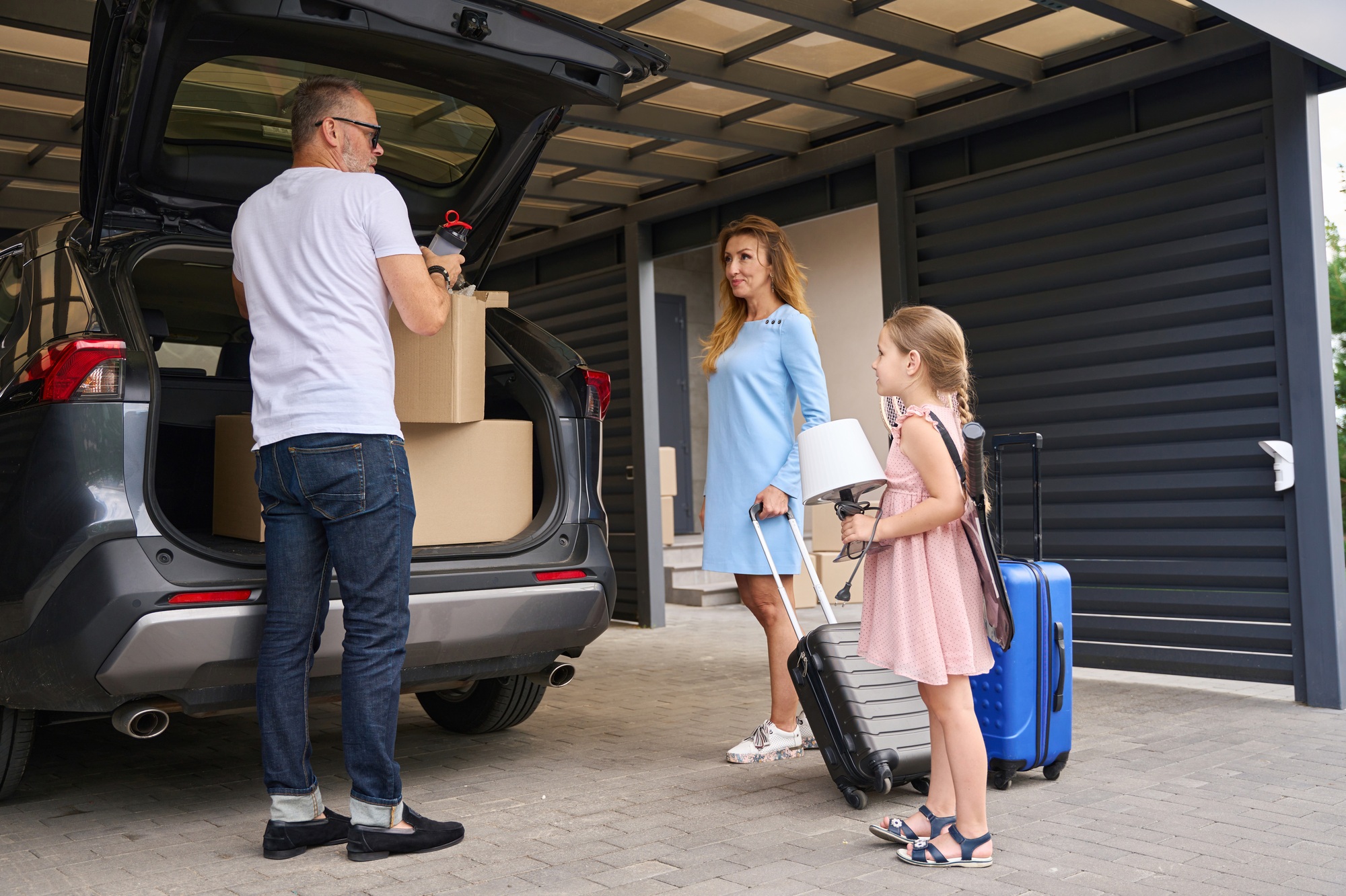 Family takes out things and boxes for moving from car